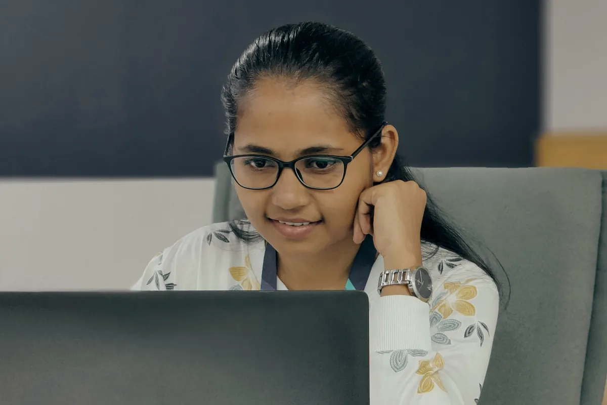 Student with glasses smiling while studying on her laptop