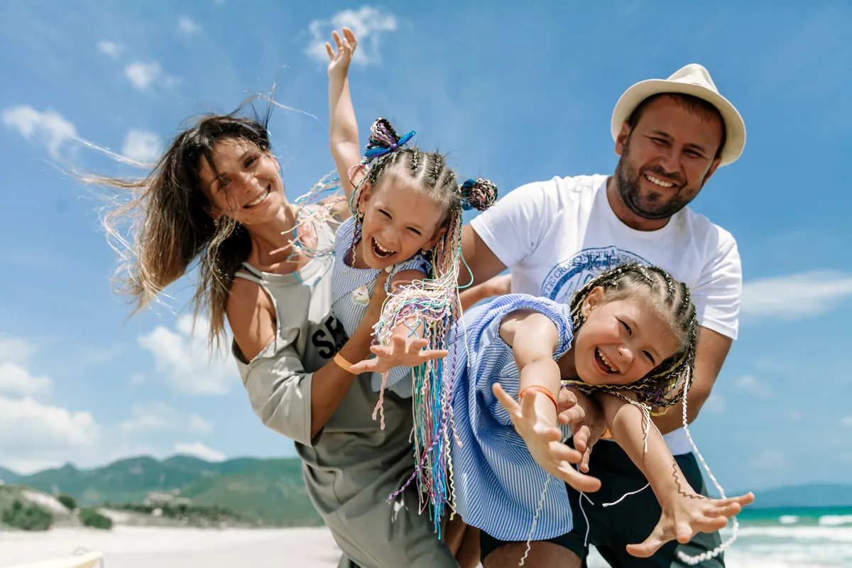 Family laughing together on a sunny beach holiday